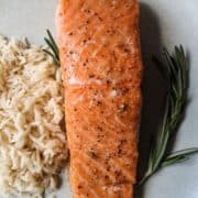 a filet of salmon with rice and rosemary on a plate