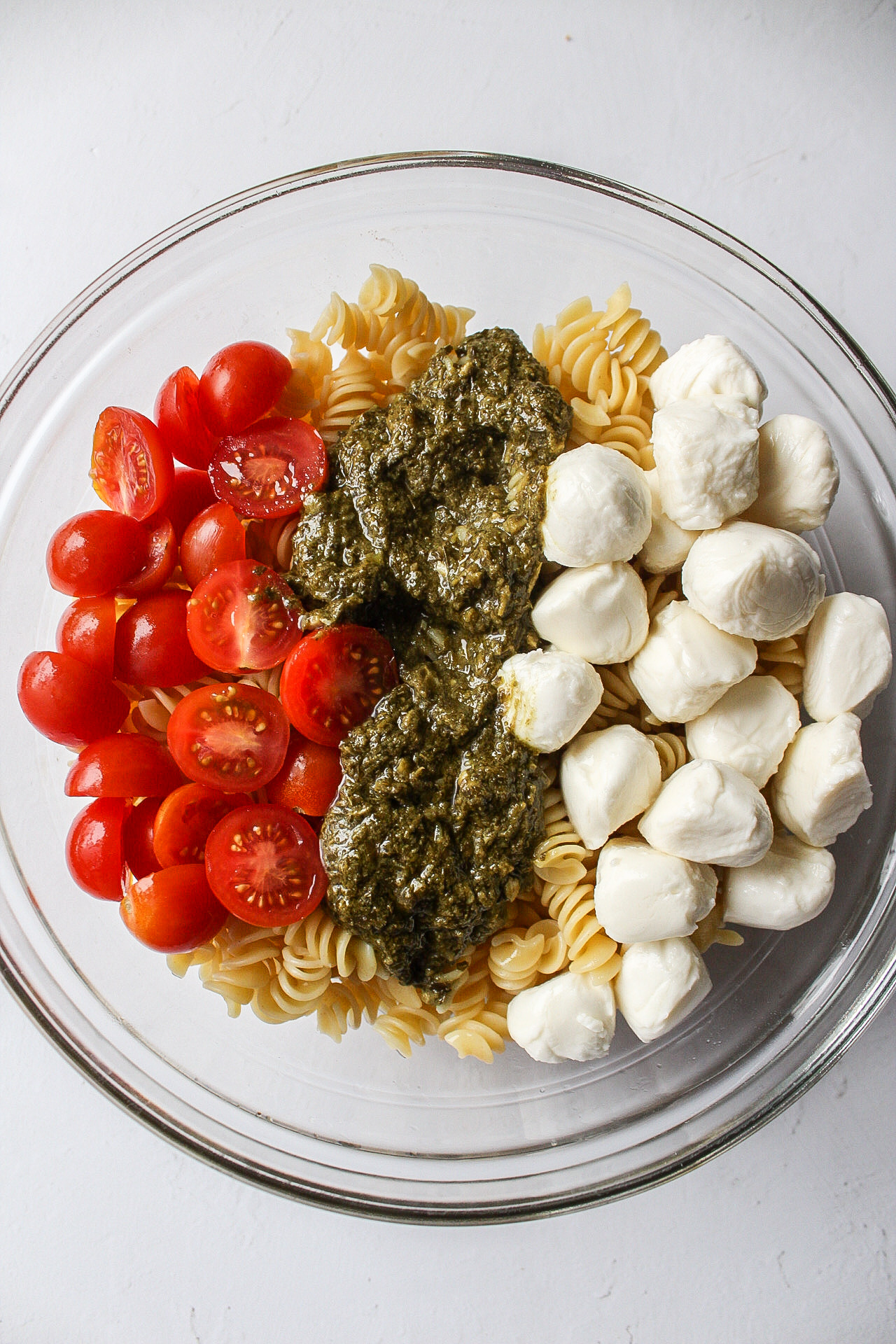 pesto, mozzarella, tomatoes, and pasta in a bowl