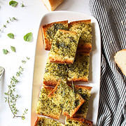 a plate of garlic bread with herbs around it