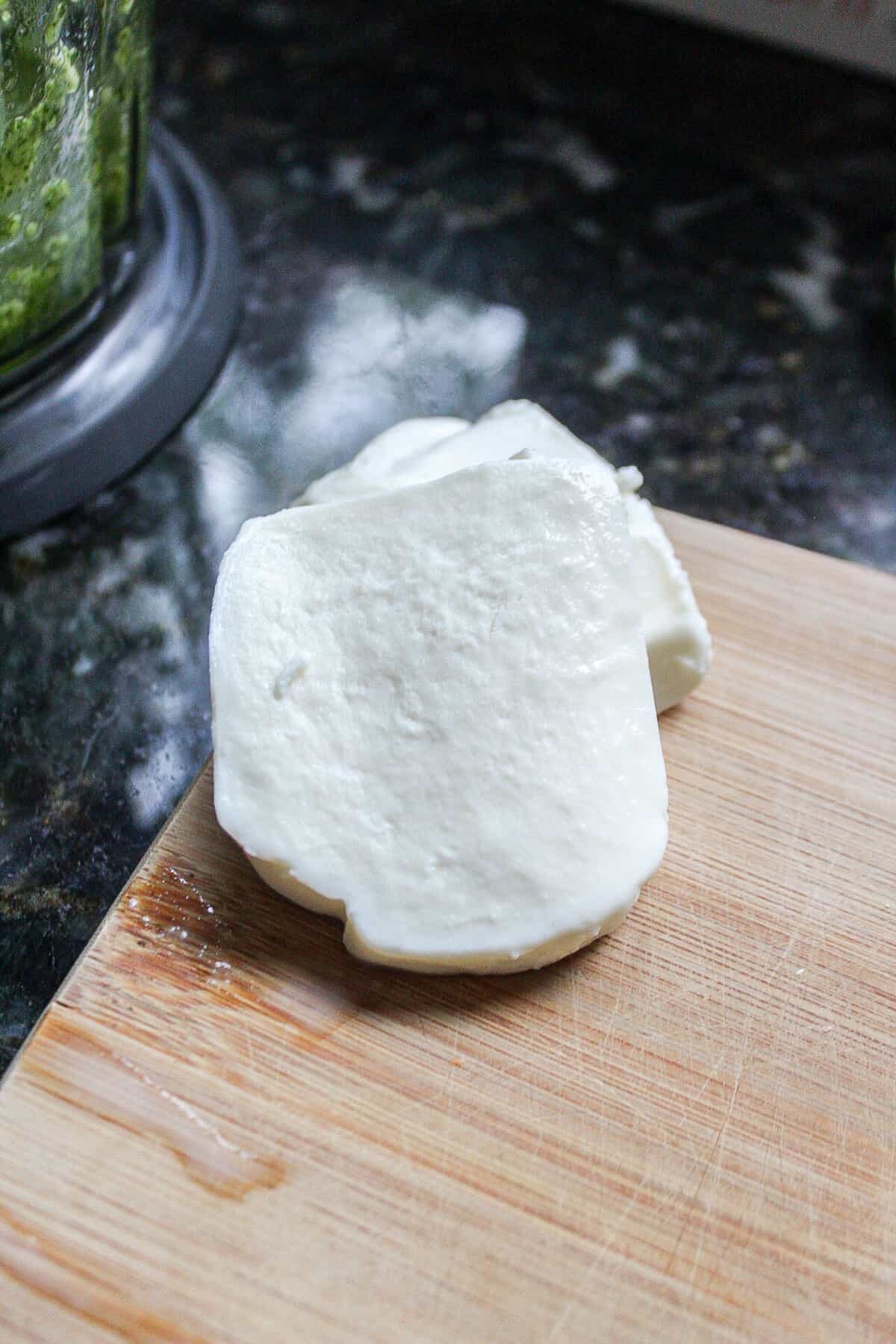 a slice of mozzarella cheese on a cutting board