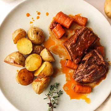 boneless braised short ribs on a plate with carrots and potatoes