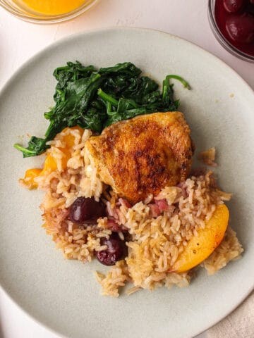 oven baked chicken with rice and fruit on a plate