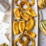 a plate of roasted delicata and acorn squash with fall decorations