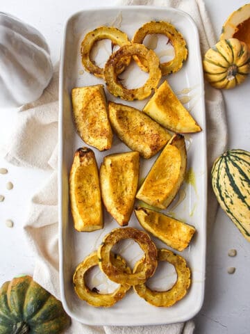 a plate of roasted delicata and acorn squash with fall decorations