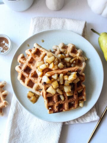 three waffles on a plate topped with pear compote