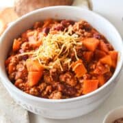 turkey chili with cheese on top in a large white bowl