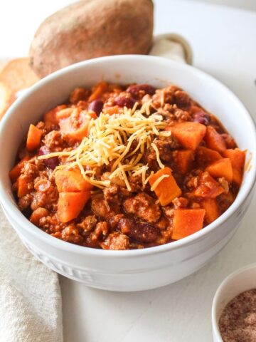 turkey chili with cheese on top in a large white bowl