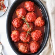 sweet and sour chicken meatballs in a black matte dish with thyme on top