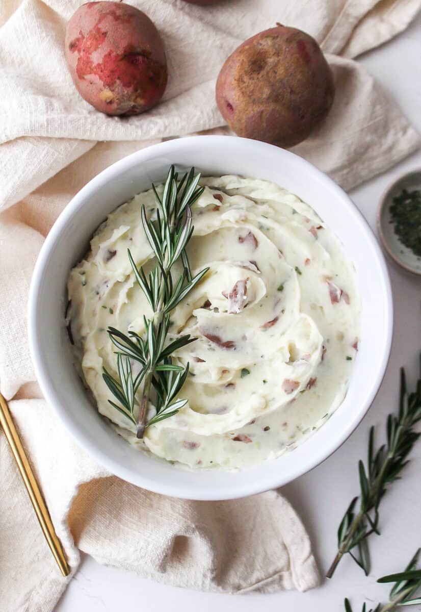 creamy garlic and herb red mashed potatoes in a bowl with rosemary on top