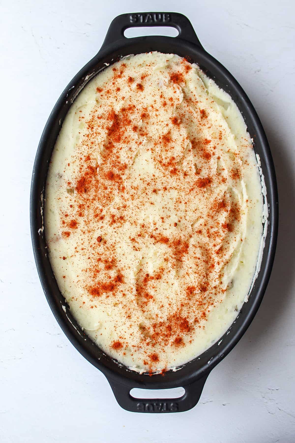 shepherd's pie in a casserole dish with mashed potatoes sprinkled with paprika on top.