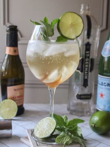 hugo spritz with mint and lime garnish in a glass.