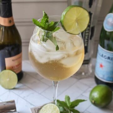 hugo spritz with mint and lime garnish in a glass.