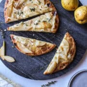 pear and brie flatbread with honey and thyme on a serving platter.