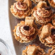 tiramisu cups on a plate with coffee soaked lady fingers and a coffee bean.