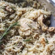 close up of a chicken thigh cooked with rice in a skillet.