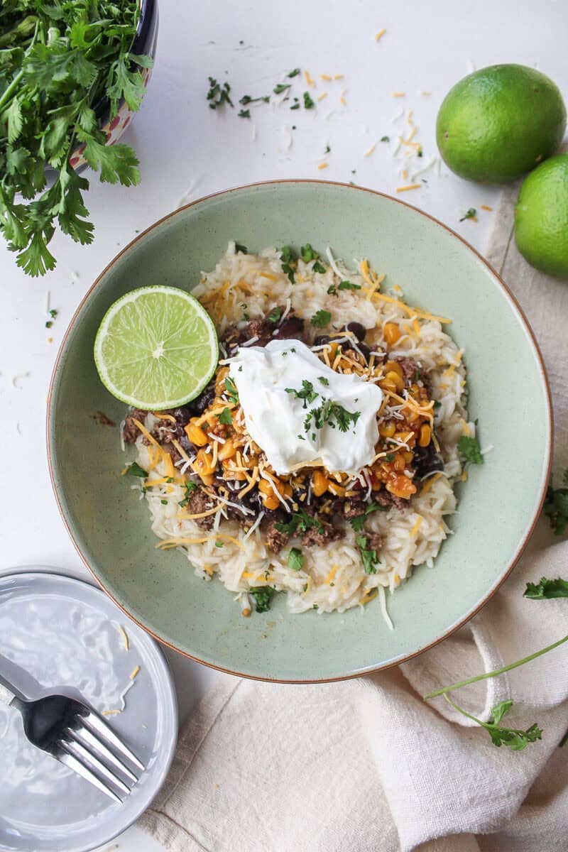 High protein ground beef taco bowl over rice with a lime.