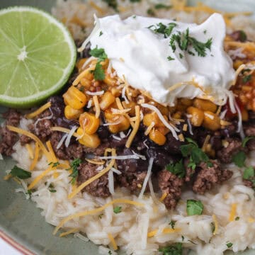 Close up of a high protein ground beef taco bowl over rice with a lime.