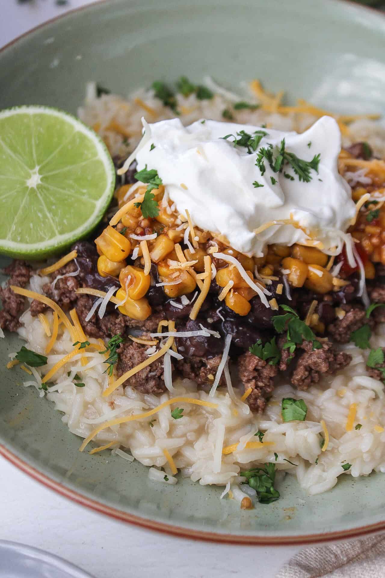 Close up of a high protein ground beef taco bowl over rice with a lime.