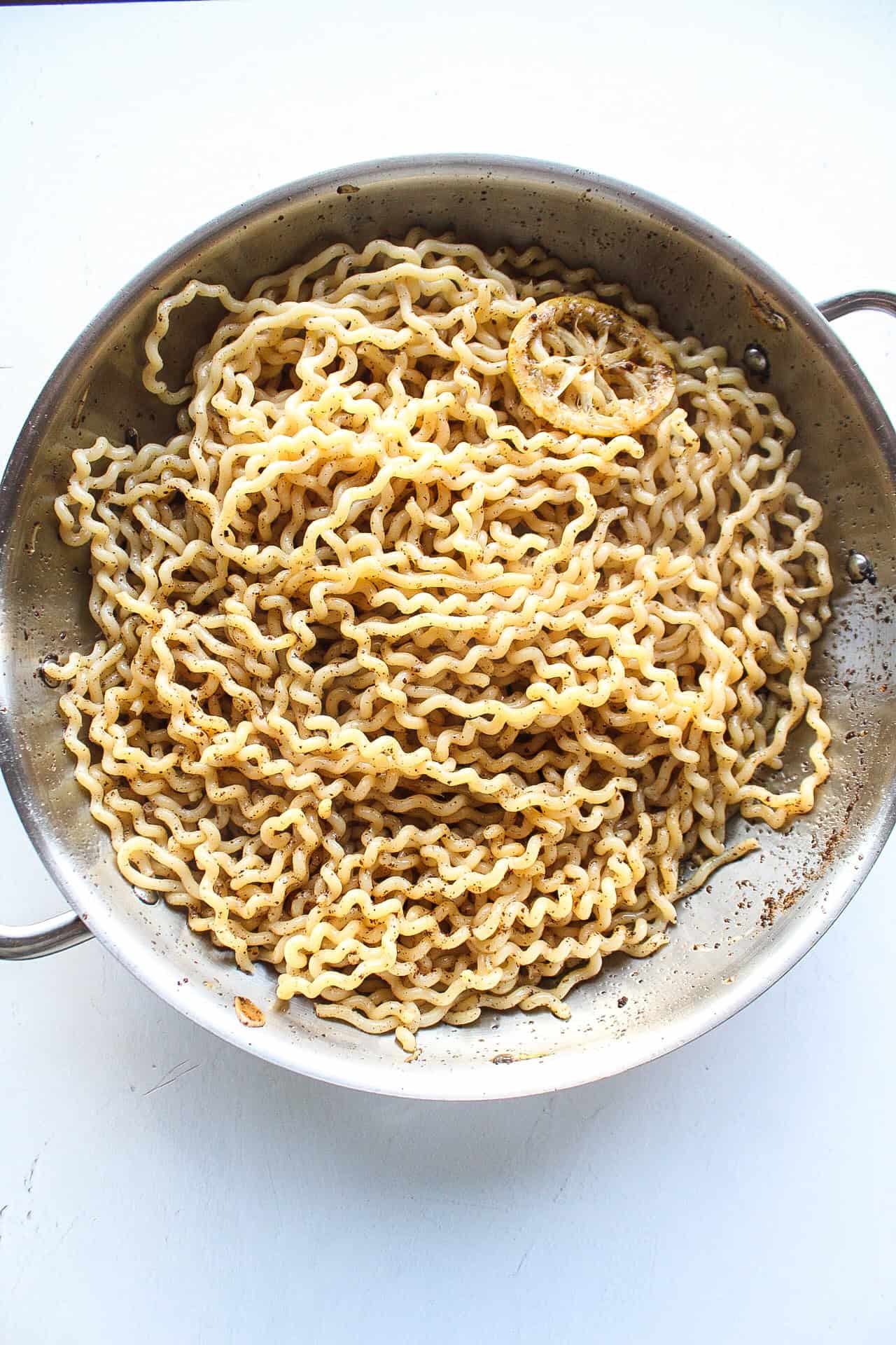 Pasta added to a skillet with a scampi sauce.