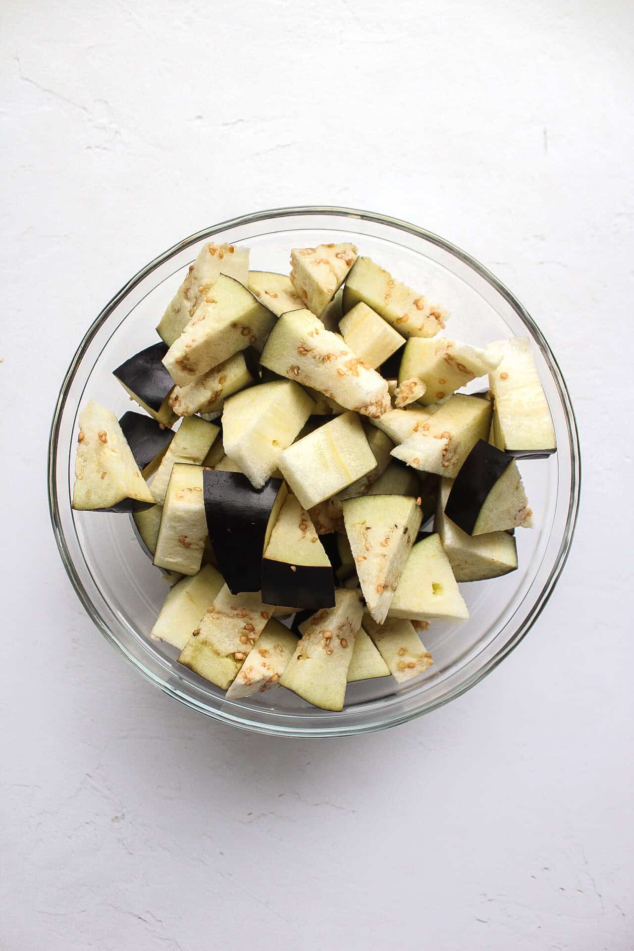 Diced eggplant in a glass bowl.