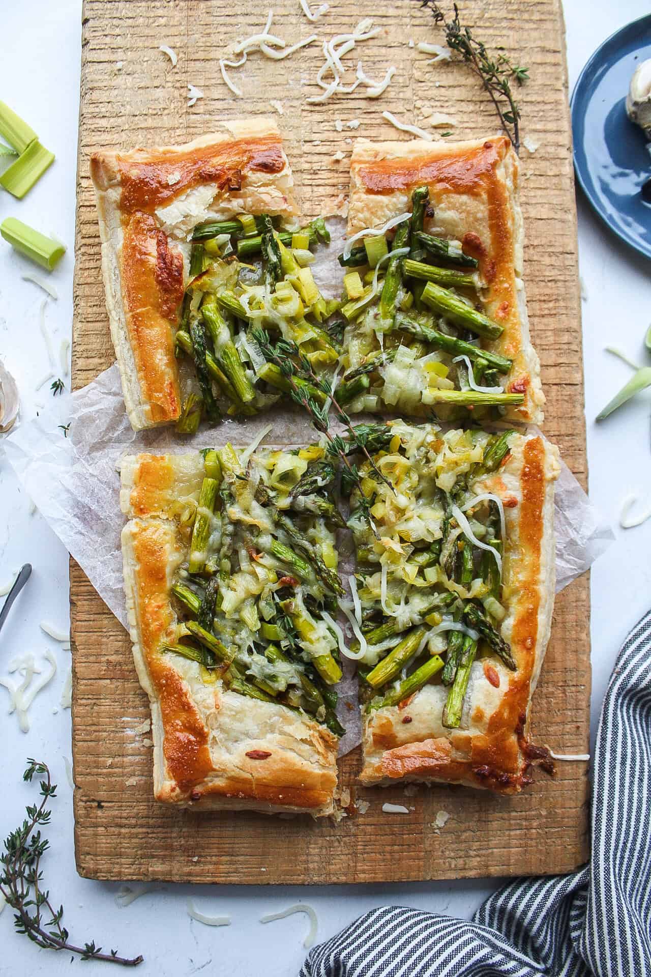 An asparagus and leek tart on cutting board with parchment paper.