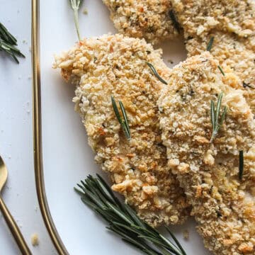Panko honey mustard chicken on a serving platter with rosemary.