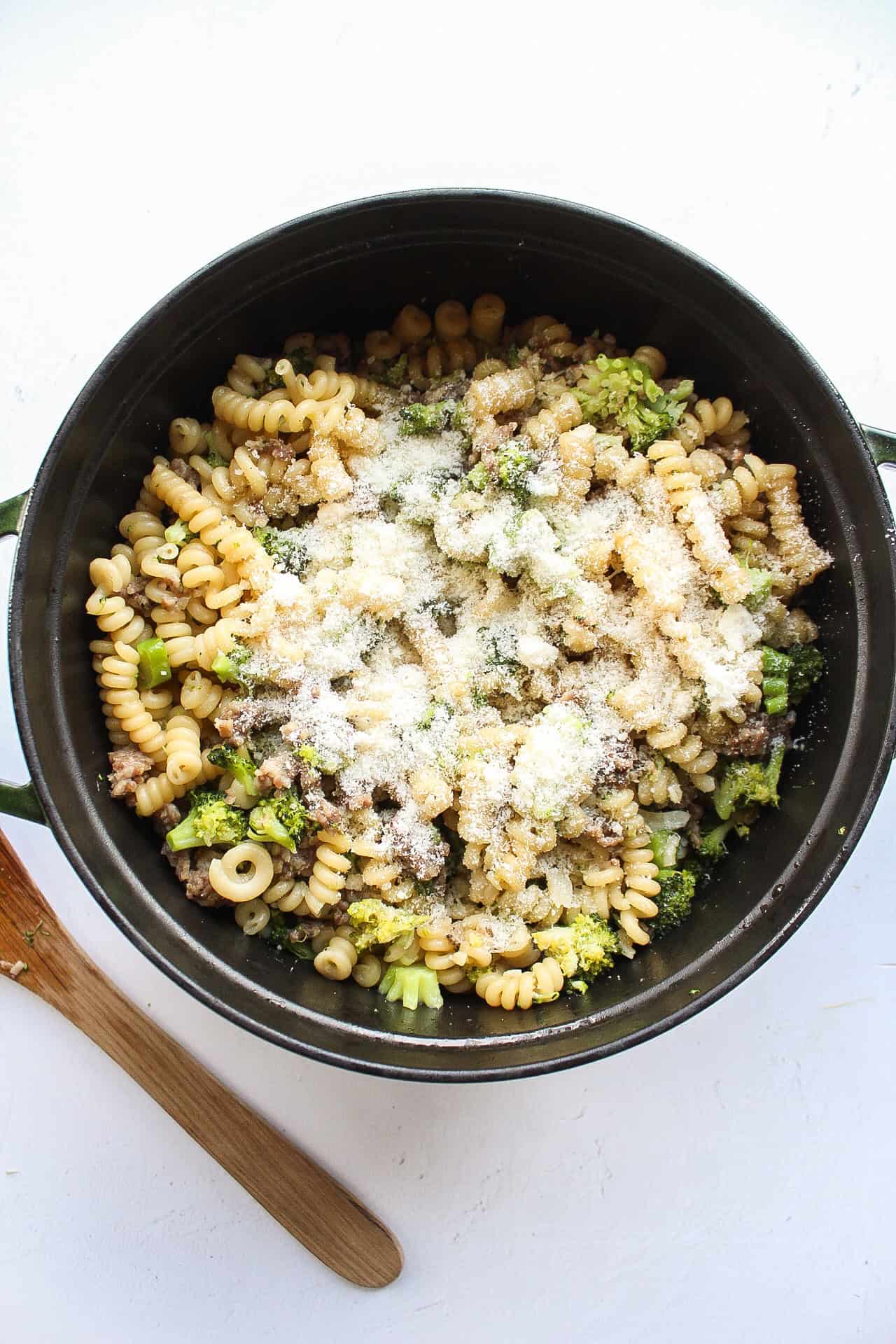Parmesan on top of cooked pasta with sausage and broccoli.