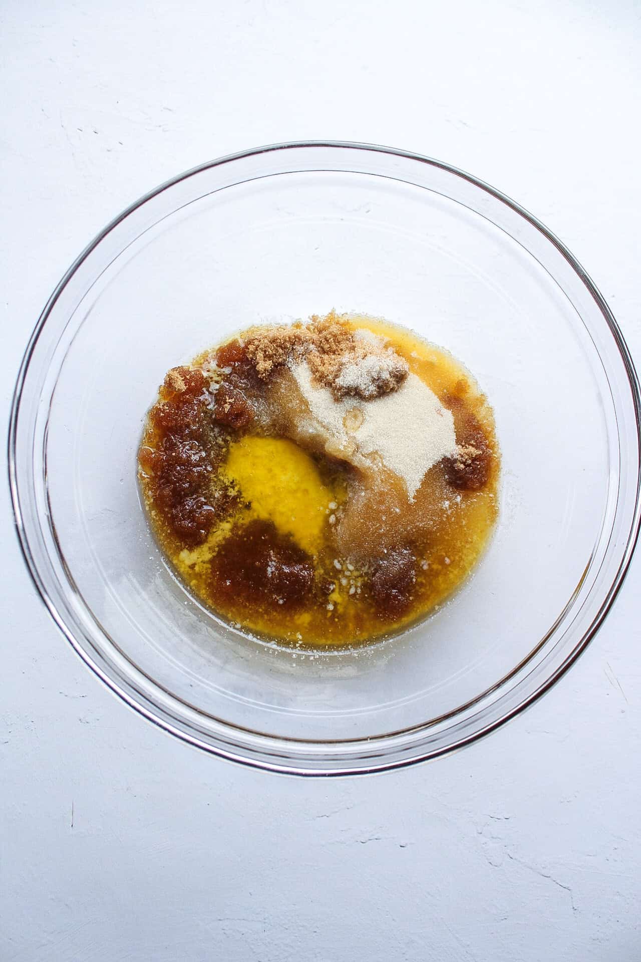 Melted butter in a bowl with brown and cane sugar.