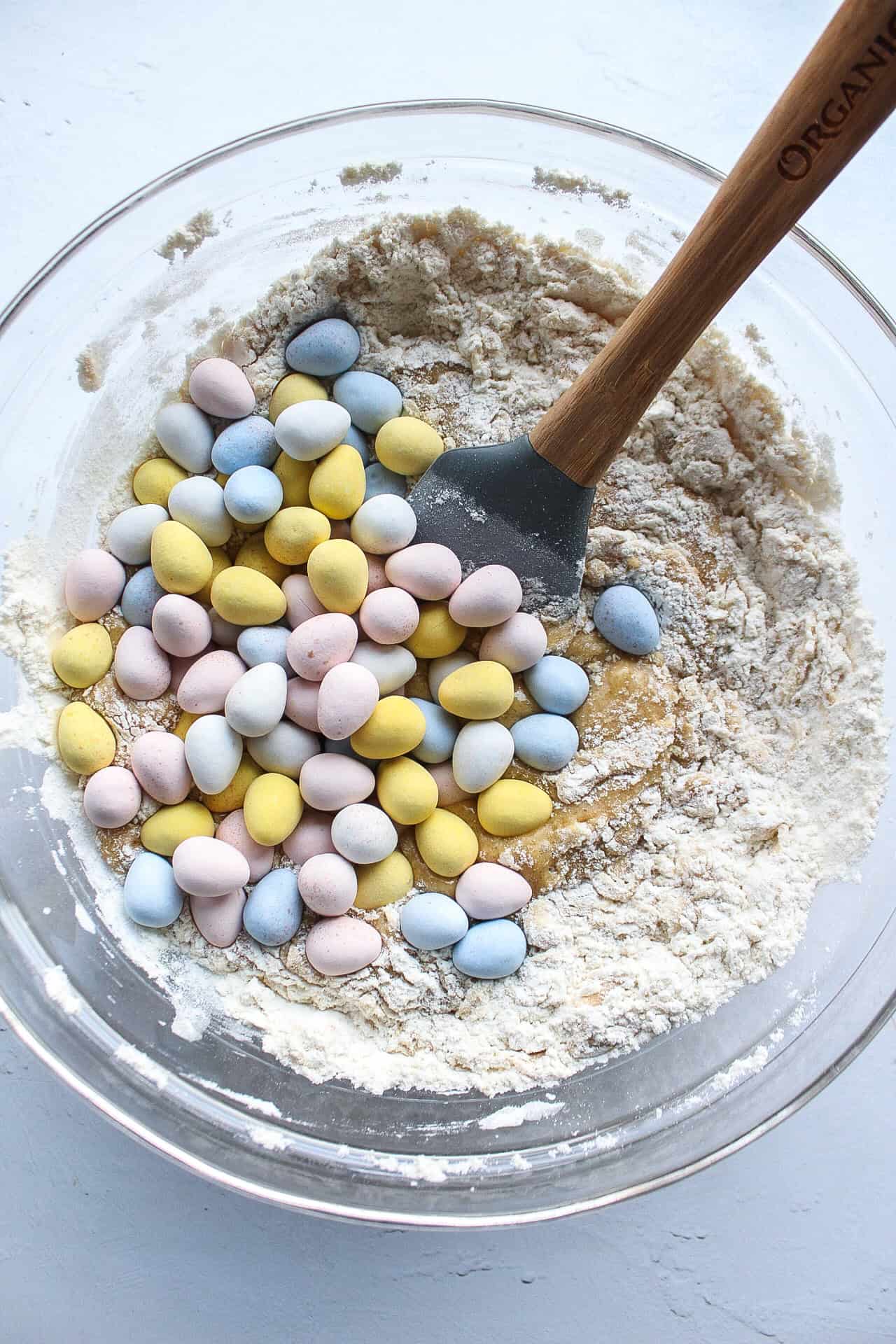 Mini cadbury eggs in a bowl of blondie batter.