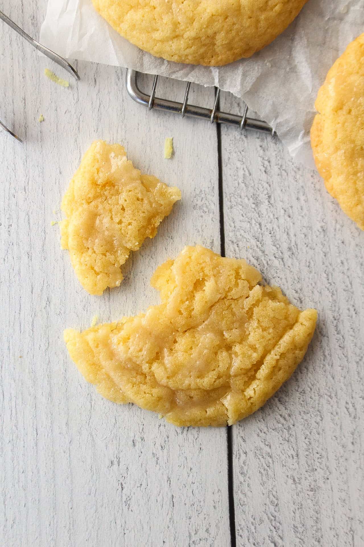 Broken lemon sugar cookie on a wooden surface.