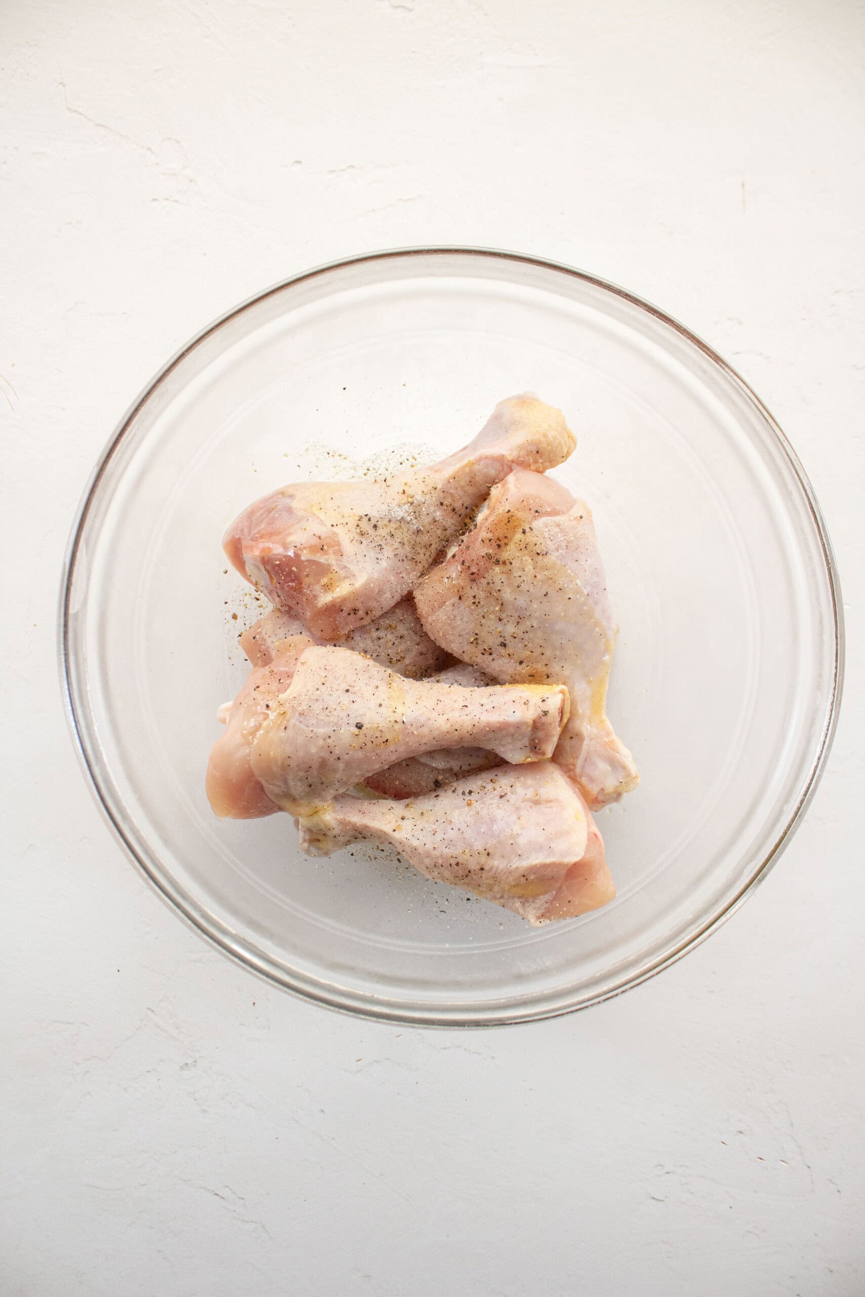 chicken drumsticks seasoned with salt pepper and olive oil.