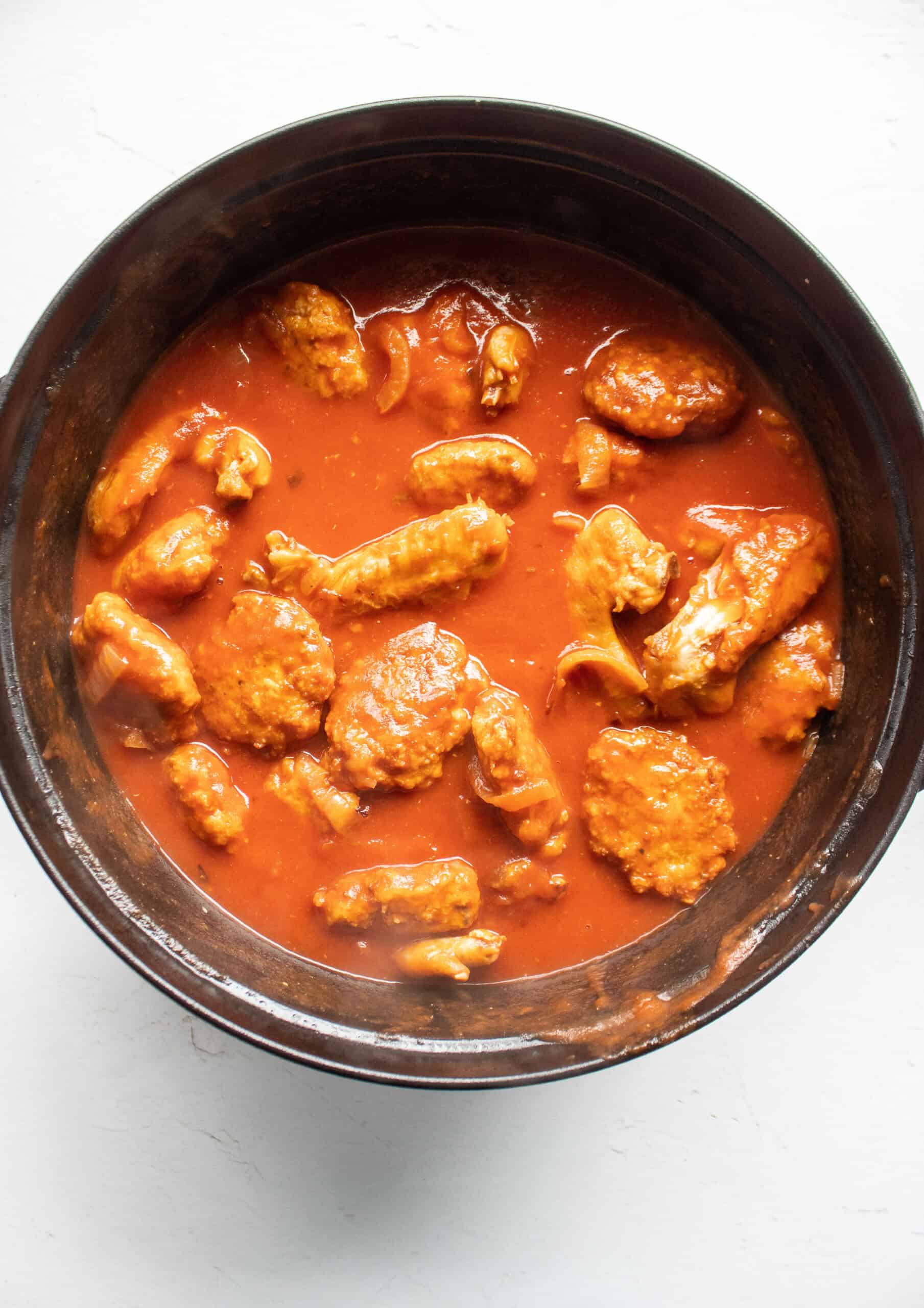 A dutch oven with sweet and tangy chicken patties and chicken wings.