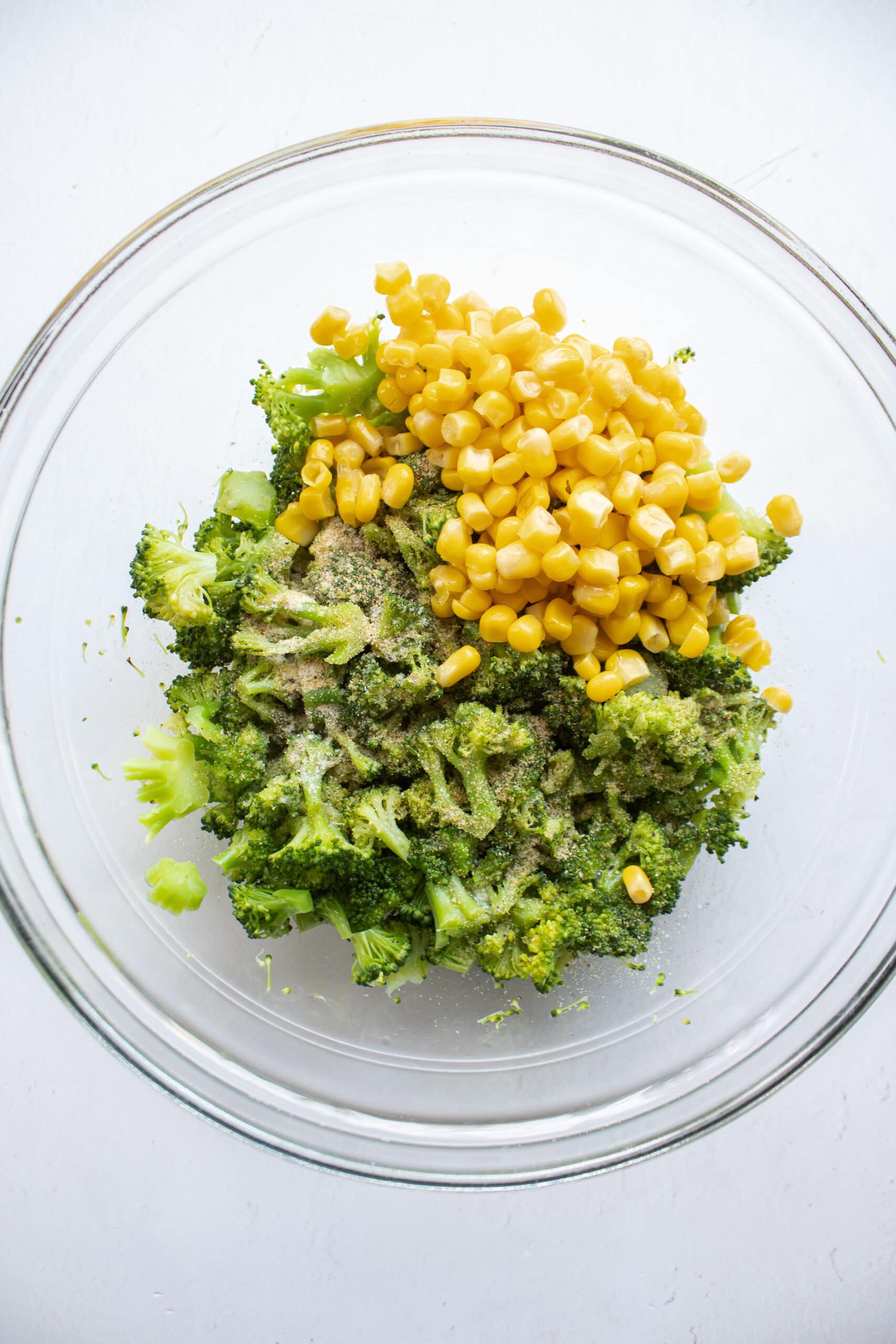 steamed and chopped broccoli in a bowl with corn and seasonings.