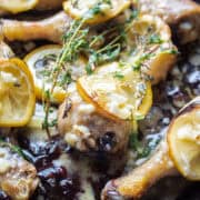close up of a piece of chicken with lemon and thyme.