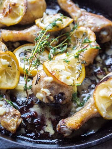 close up of a piece of chicken with lemon and thyme.