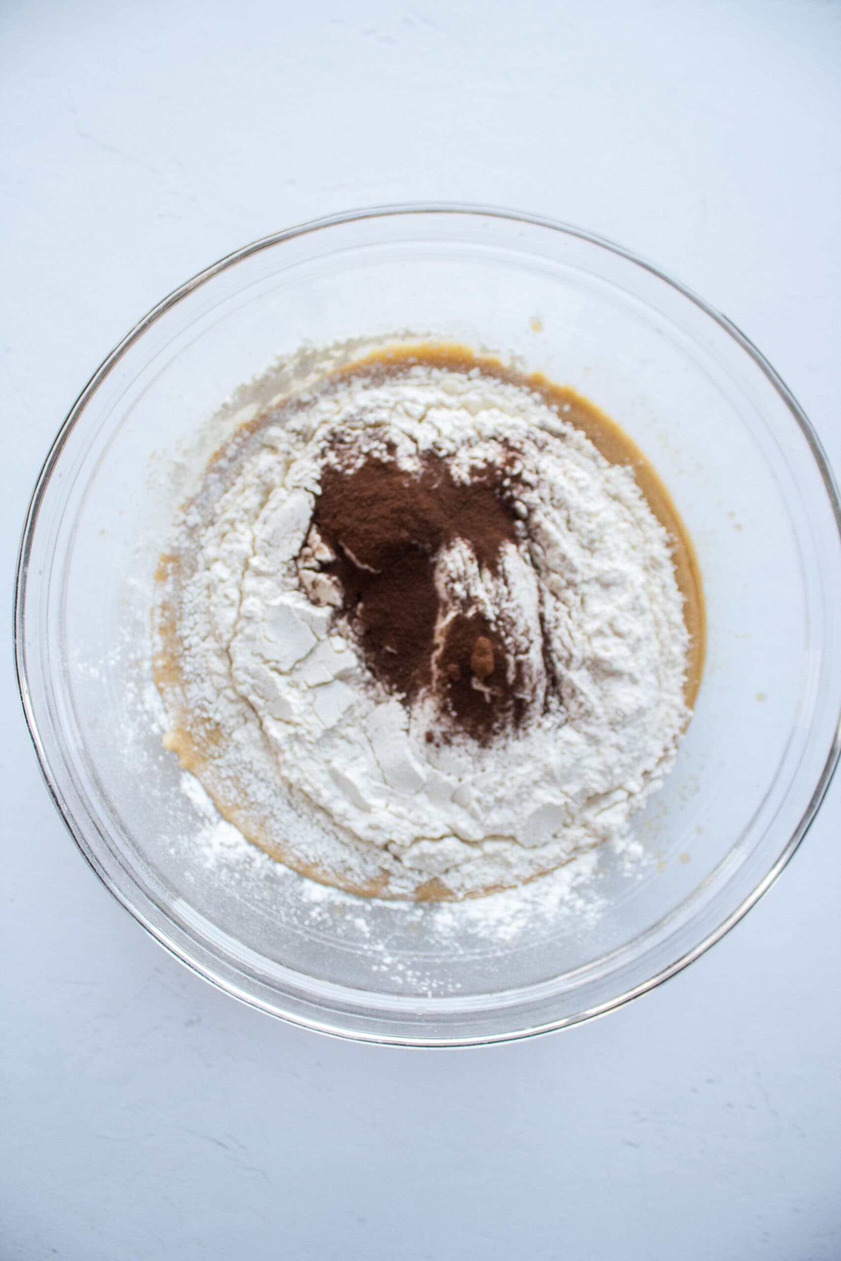 Dry ingredients added to a large mixing bowl of cookie batter including espresso powder.