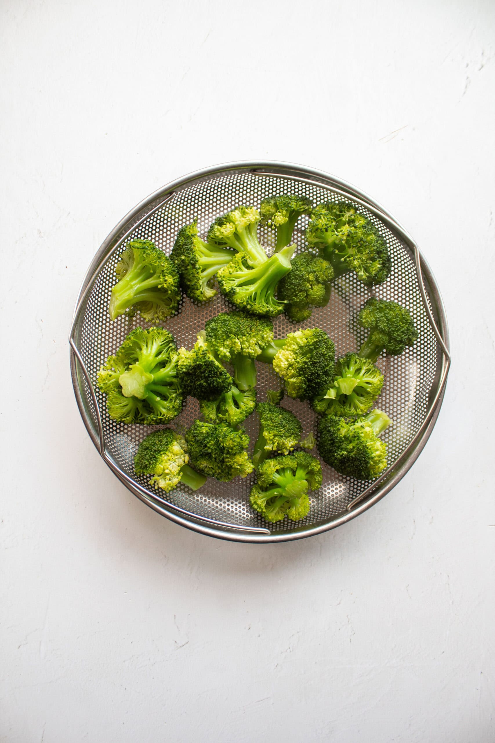 steamed broccoli in a colander.