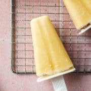 close up of a mango yogurt popsicle on a cooling rack.