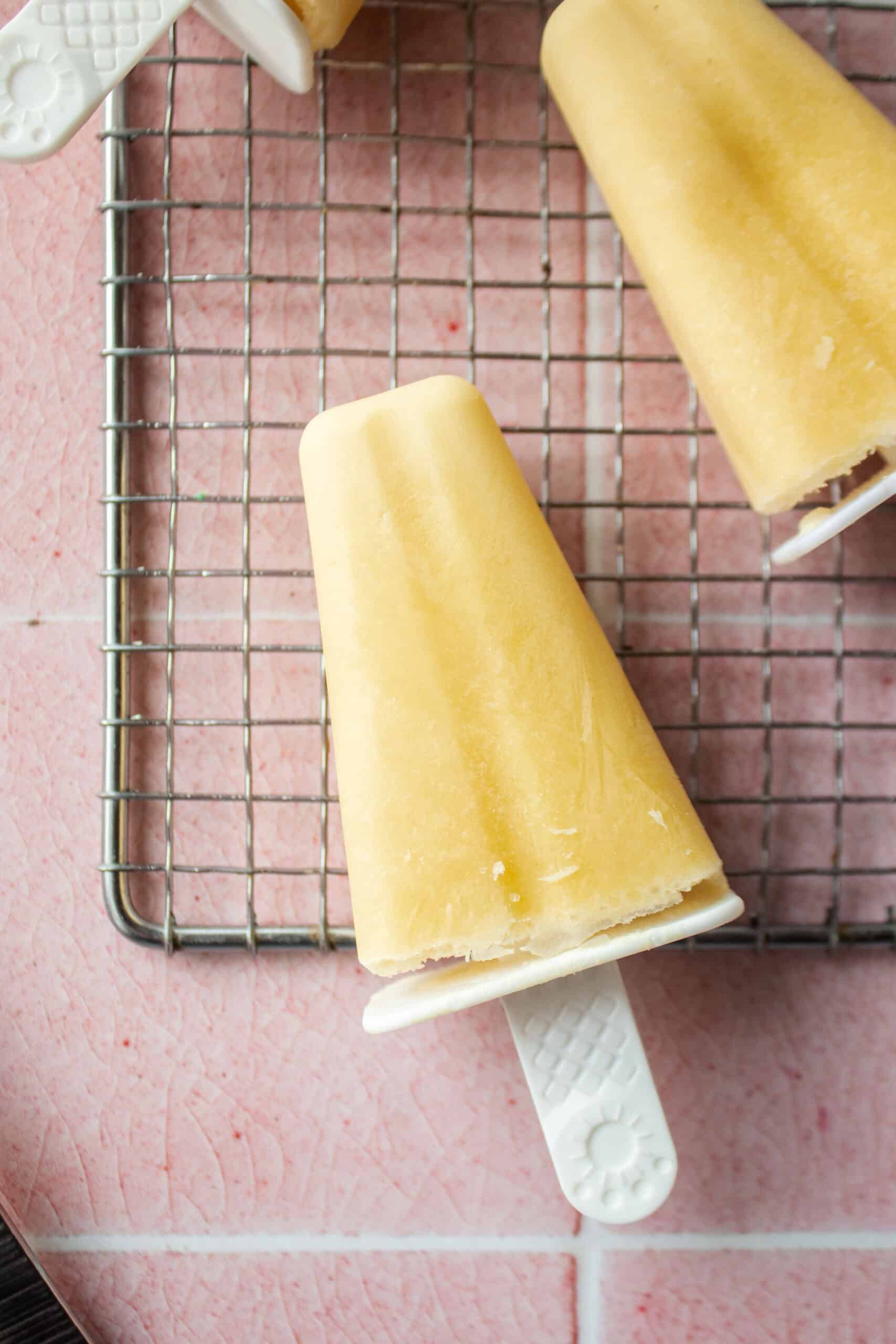 close up of a mango yogurt popsicle on a cooling rack.