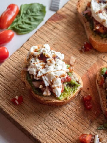 close up of bruschetta crostini topped with with burrata and balsamic glaze.
