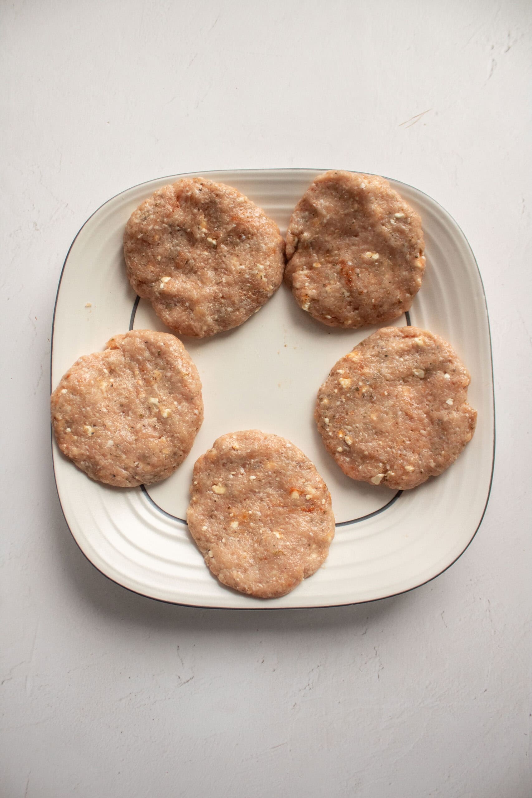 five chicken burgers on a plate.