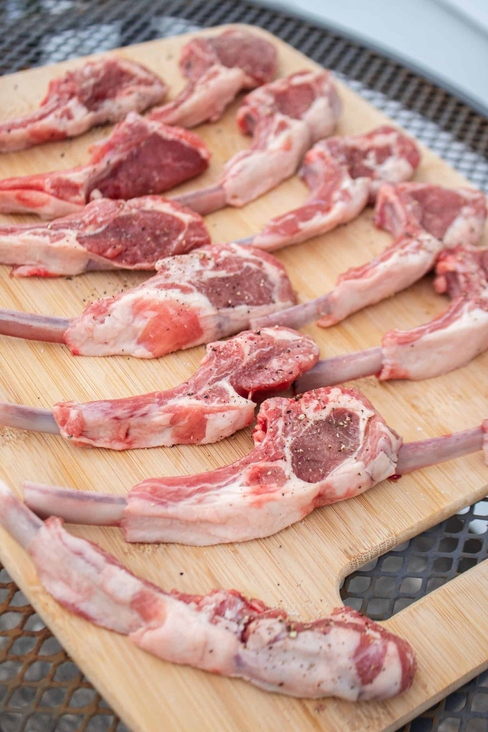 lamb chops on a cutting board seasoned with salt and pepper.
