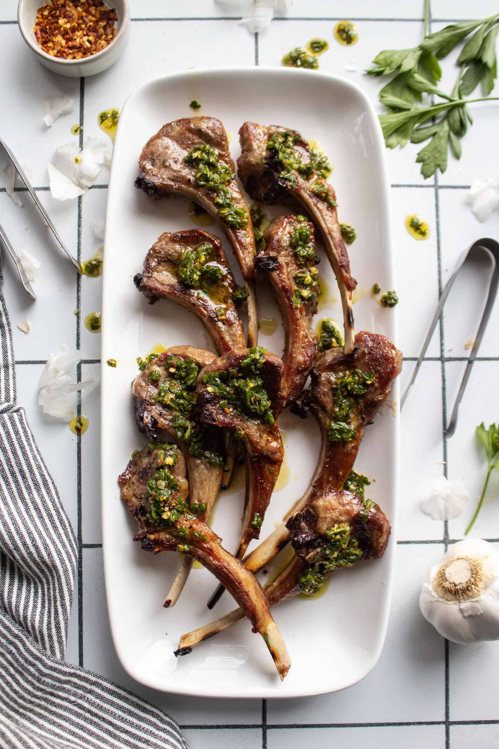 lamb chops on a plate with chimichurri sauce on top.