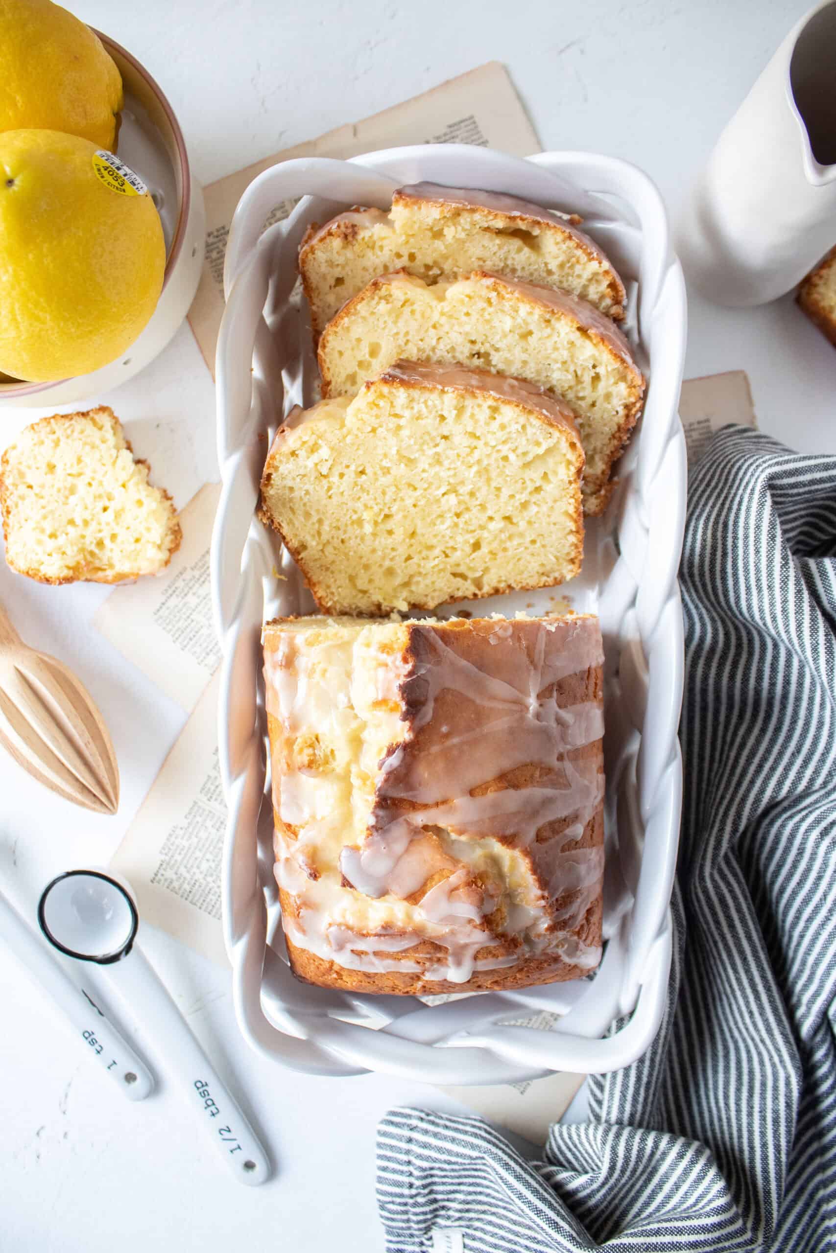 sliced lemon loaf cake in a porcelain basket with glaze on top.