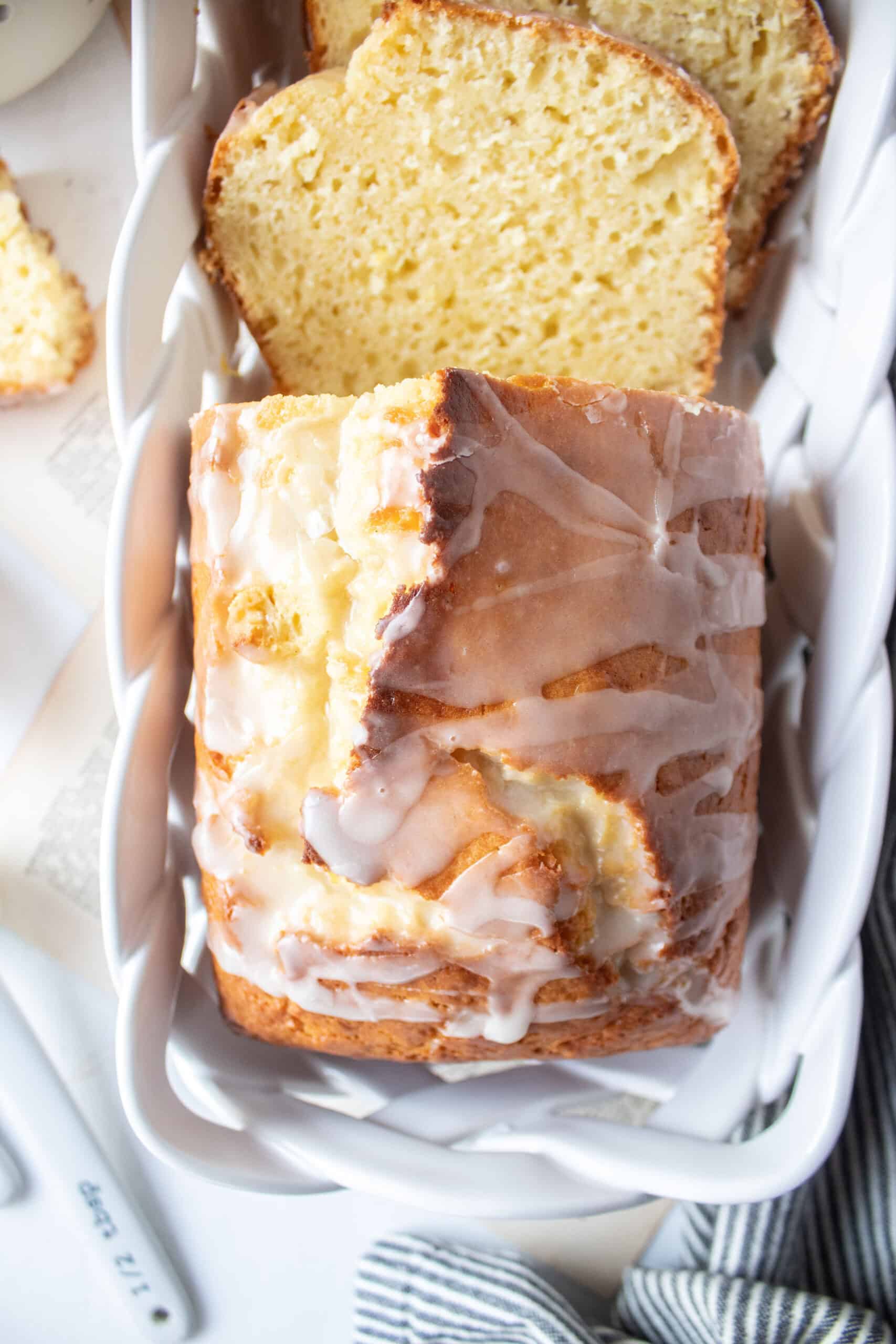 sliced lemon loaf cake in a porcelain basket with glaze on top.