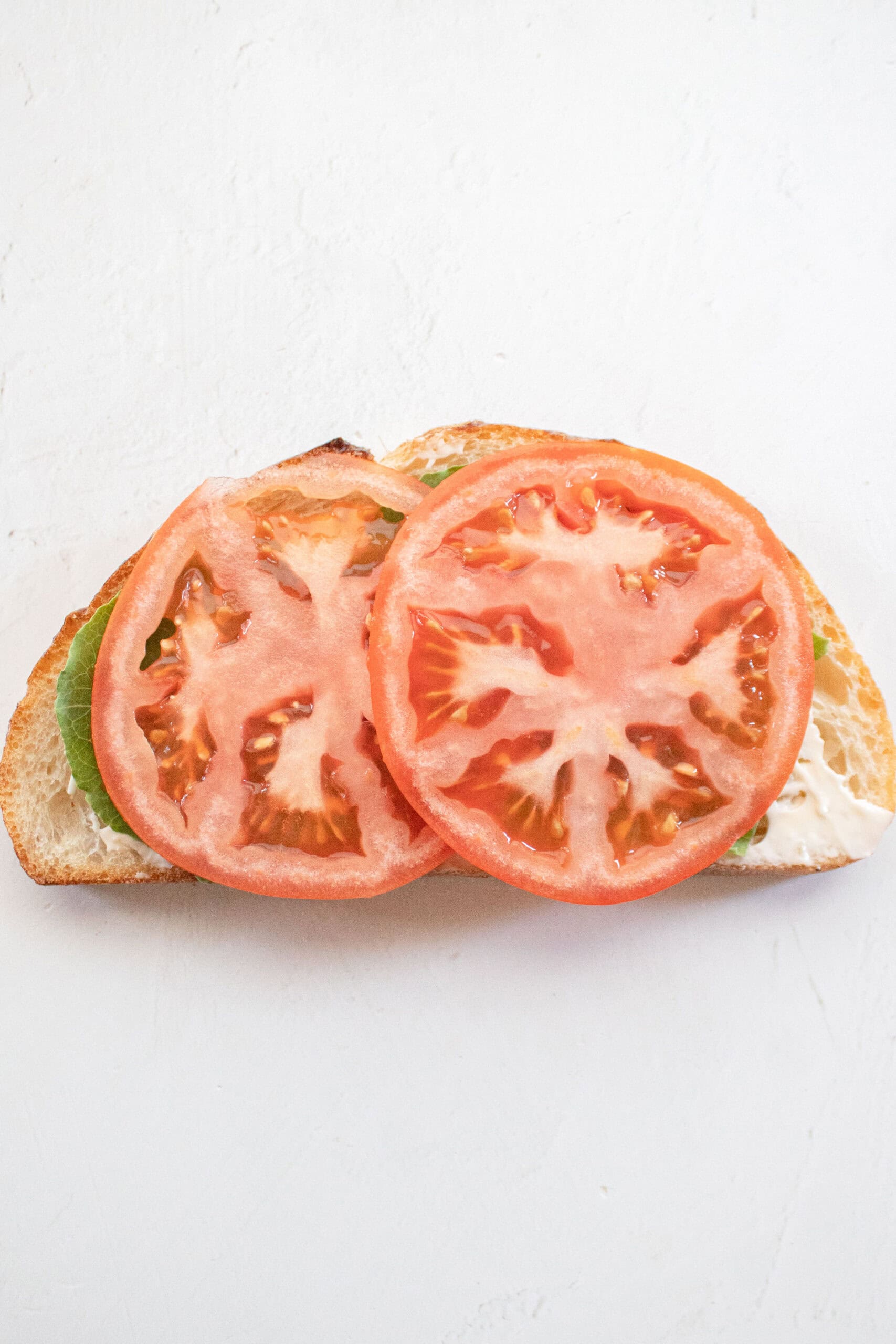 Sliced tomato and lettuce on sourdough with mayo.