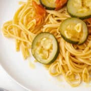 Close up of zucchini on a plate of linguine with garlic.