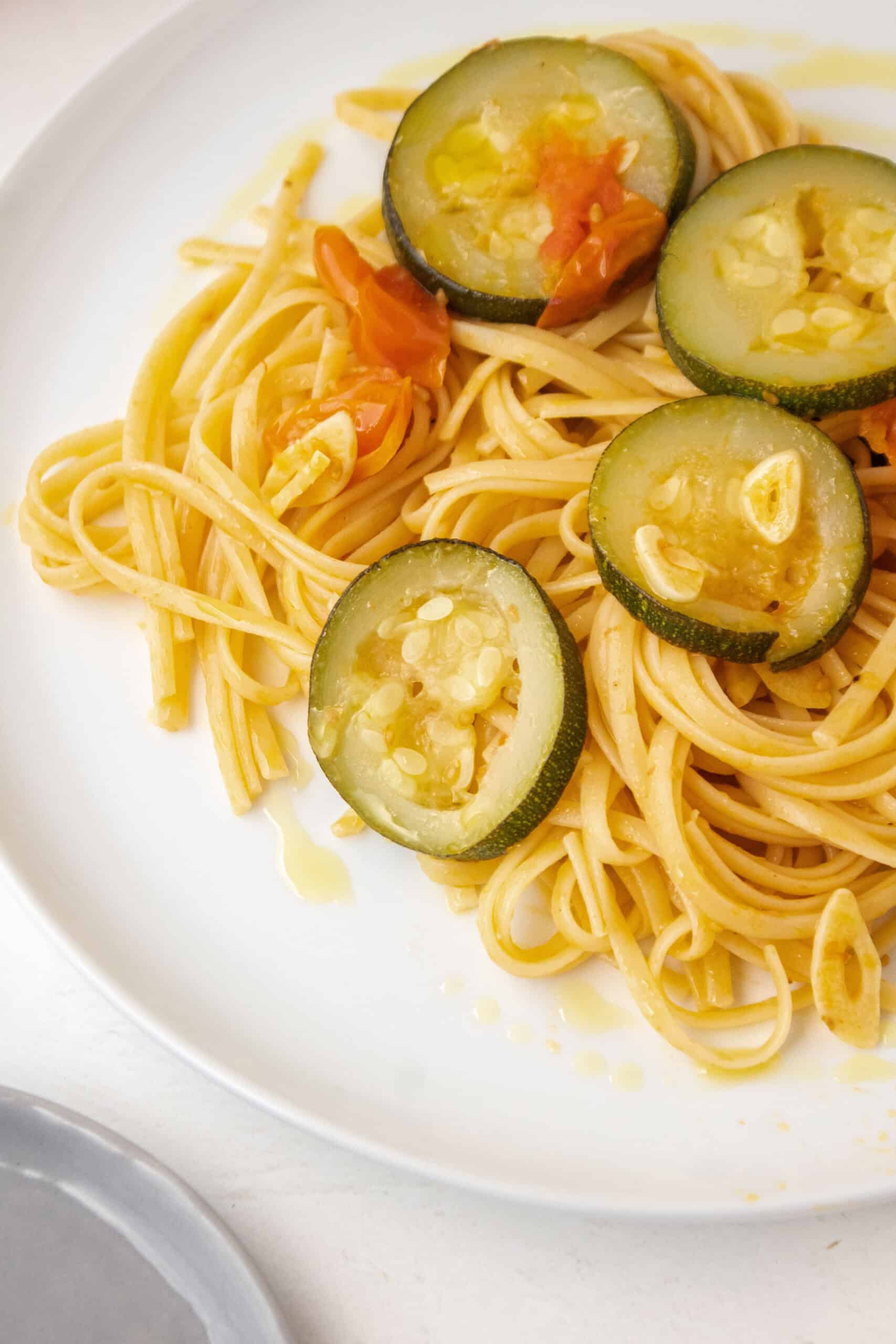 Close up of zucchini on a plate of linguine with garlic.