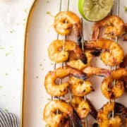 shrimp skewers on a plate with lime.