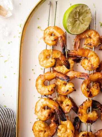 shrimp skewers on a plate with lime.